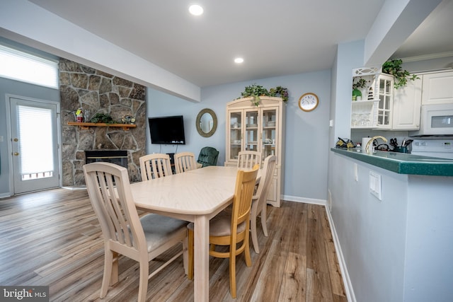 dining area with a stone fireplace and light hardwood / wood-style flooring