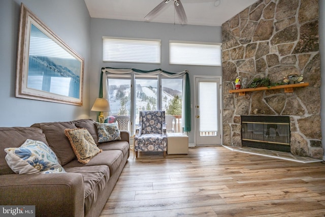 living room featuring light hardwood / wood-style flooring, ceiling fan, a towering ceiling, a fireplace, and a mountain view