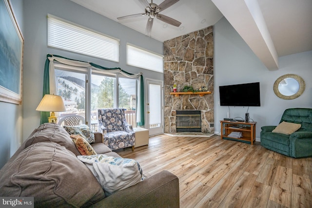 living room featuring ceiling fan, high vaulted ceiling, a fireplace, and light wood-type flooring