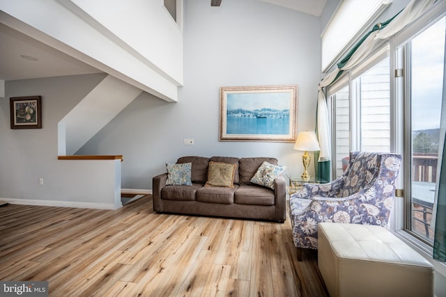 living room with a towering ceiling and light wood-type flooring