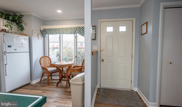 entrance foyer featuring ornamental molding, a healthy amount of sunlight, and light wood-type flooring