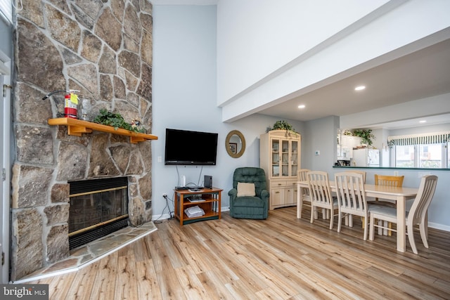 dining area featuring a towering ceiling, a fireplace, and light hardwood / wood-style floors