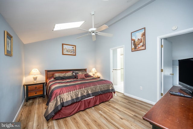 bedroom with ceiling fan, vaulted ceiling with skylight, and light wood-type flooring