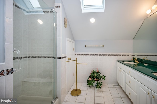 bathroom featuring walk in shower, lofted ceiling with skylight, tile walls, vanity, and tile patterned flooring