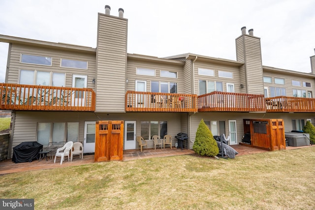 rear view of house featuring a lawn, an outdoor hot tub, and a patio area