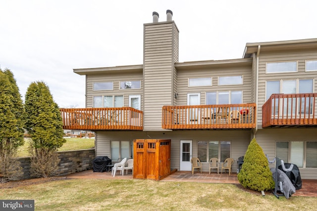 rear view of property with a deck, a patio, and a lawn