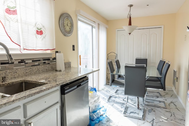 kitchen with sink, dishwasher, pendant lighting, light stone countertops, and white cabinets