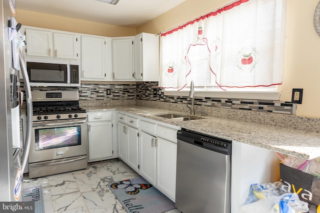 kitchen featuring sink, backsplash, white cabinets, light stone counters, and stainless steel appliances