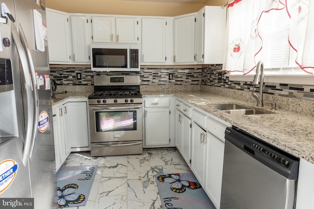 kitchen featuring light stone countertops, appliances with stainless steel finishes, sink, and white cabinets