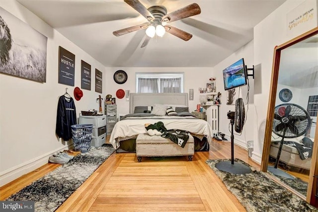 bedroom featuring hardwood / wood-style flooring, radiator heating unit, and ceiling fan