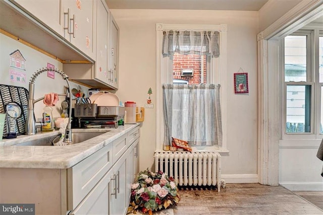 kitchen featuring sink, radiator heating unit, and white cabinets