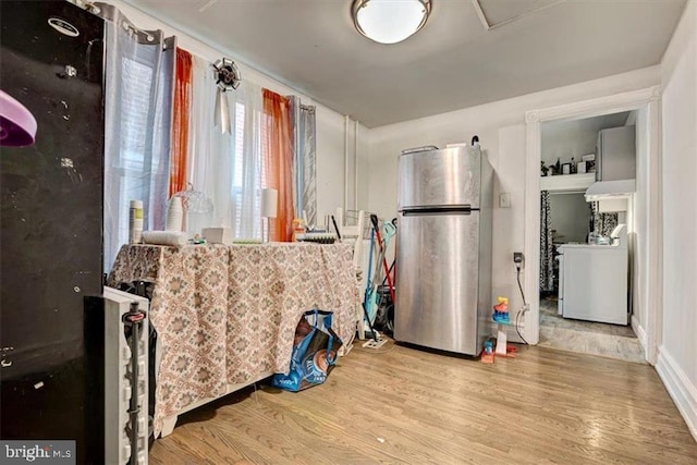 kitchen featuring washer / dryer, stainless steel fridge, and light hardwood / wood-style flooring