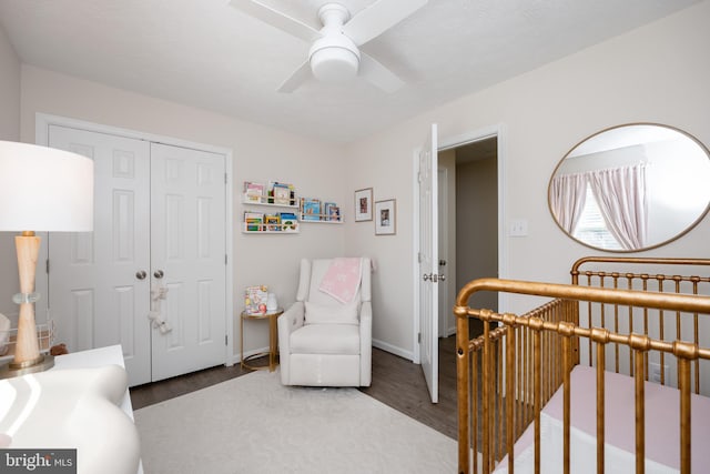 bedroom with a nursery area, ceiling fan, a closet, and hardwood / wood-style flooring