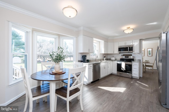 kitchen with white cabinetry, appliances with stainless steel finishes, dark wood-type flooring, and crown molding