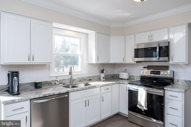 kitchen with sink, white cabinetry, crown molding, stainless steel appliances, and decorative backsplash