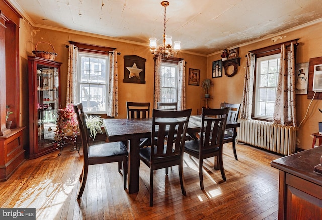 dining space featuring crown molding, radiator heating unit, an inviting chandelier, and hardwood / wood-style flooring