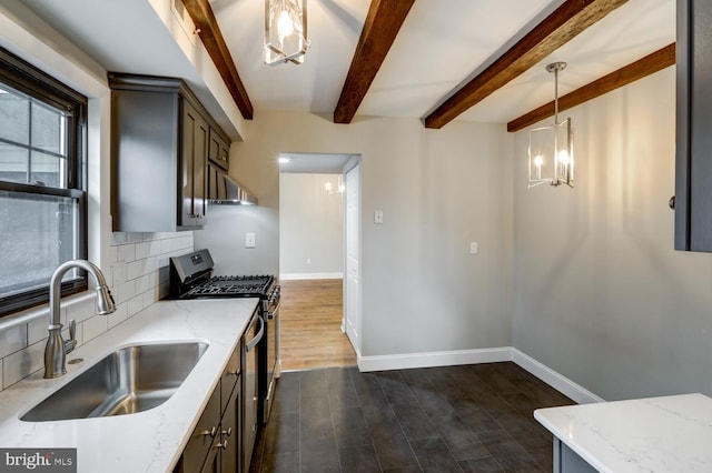 kitchen featuring sink, light stone counters, stainless steel gas range oven, decorative backsplash, and decorative light fixtures