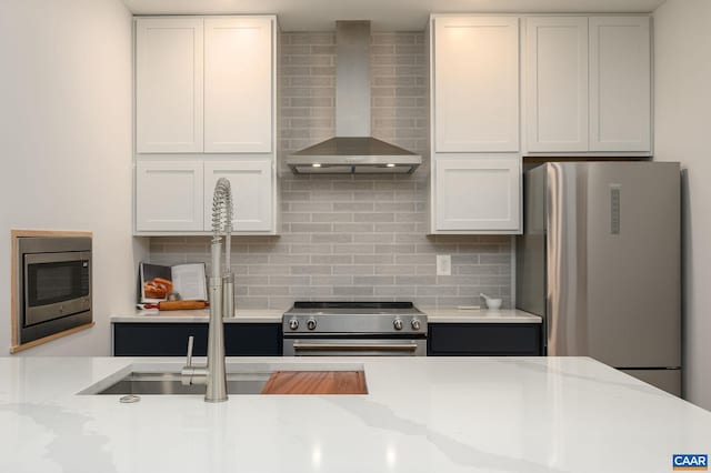 kitchen with white cabinets, appliances with stainless steel finishes, and wall chimney range hood