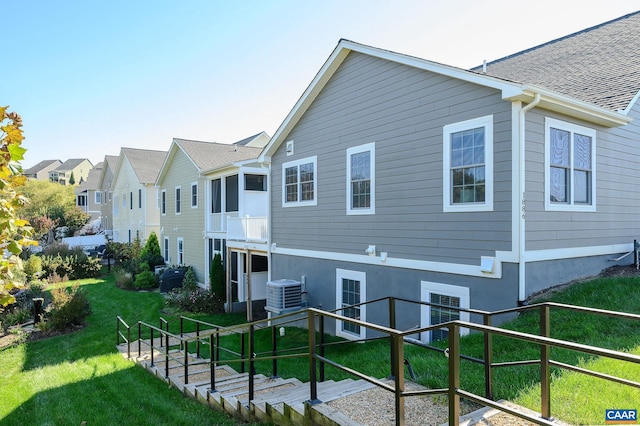 back of house featuring a lawn and central air condition unit