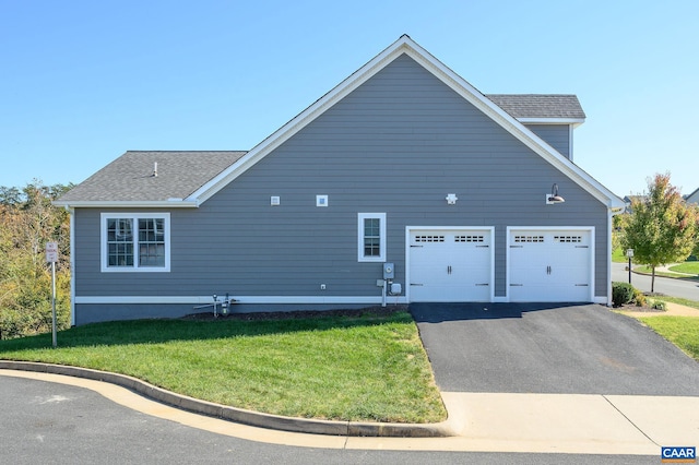 view of side of property featuring a garage and a lawn