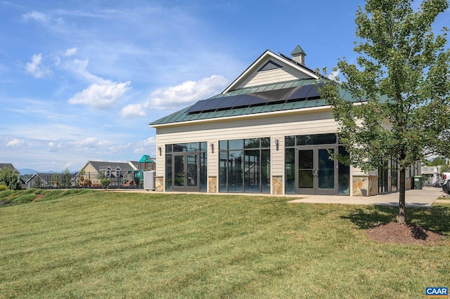 rear view of house with a yard and solar panels