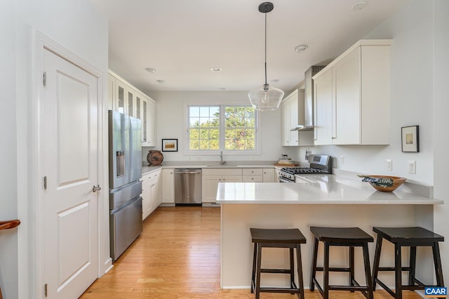 kitchen featuring appliances with stainless steel finishes, a kitchen breakfast bar, white cabinets, decorative light fixtures, and kitchen peninsula