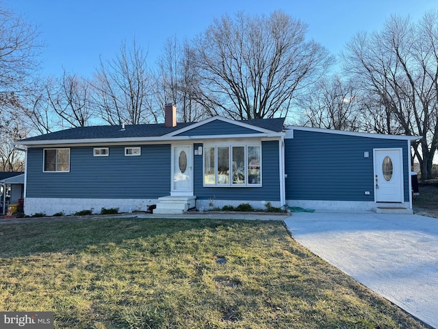 view of front of property with entry steps, a chimney, concrete driveway, and a front yard