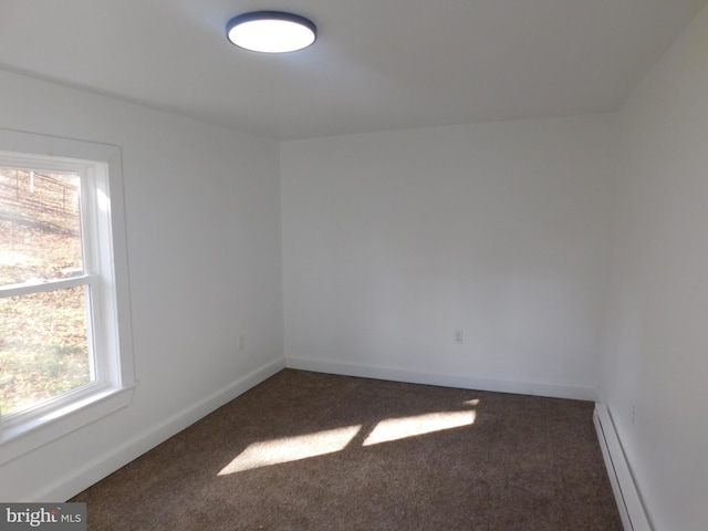 spare room featuring dark carpet and baseboard heating