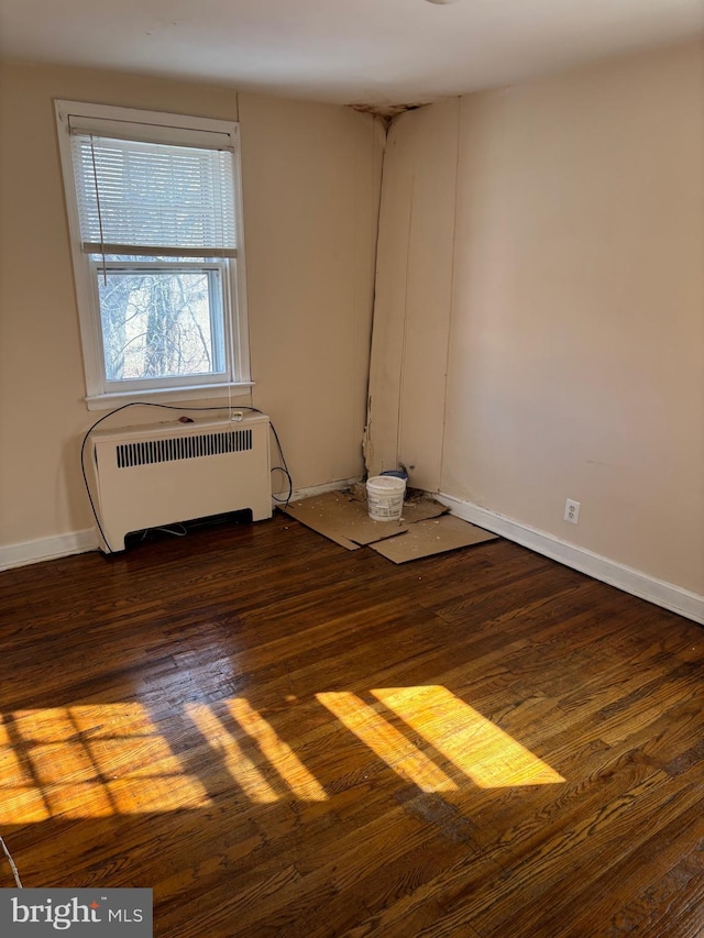 spare room with radiator and dark hardwood / wood-style floors