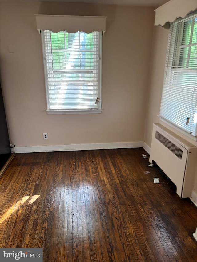 unfurnished dining area featuring radiator heating unit and dark hardwood / wood-style floors