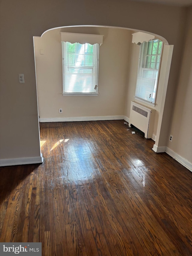 empty room featuring radiator heating unit and dark hardwood / wood-style floors