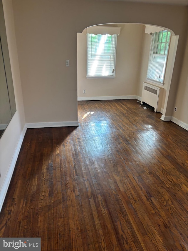 unfurnished room featuring dark wood-type flooring and radiator