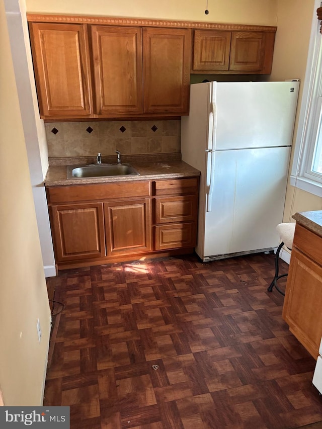 kitchen featuring sink, dark parquet flooring, decorative backsplash, and white fridge