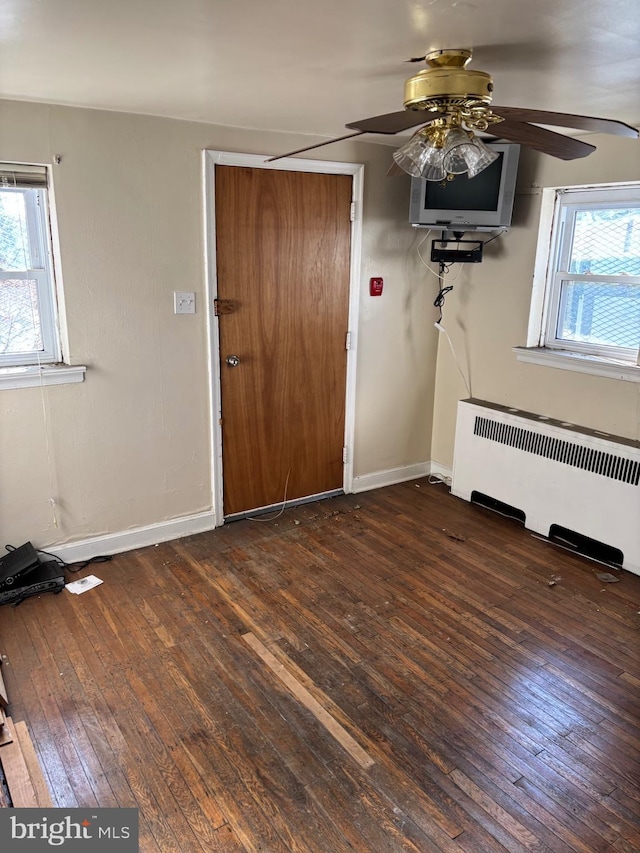 interior space with ceiling fan, plenty of natural light, radiator, and dark hardwood / wood-style flooring