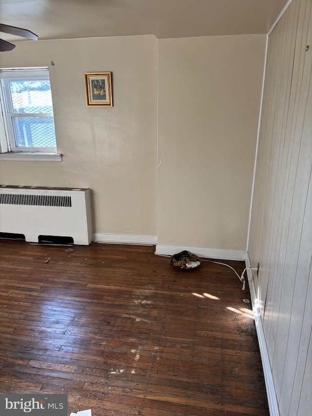 empty room with radiator, dark hardwood / wood-style floors, and ceiling fan