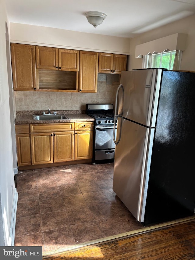 kitchen with sink, stainless steel fridge, range with gas cooktop, and decorative backsplash