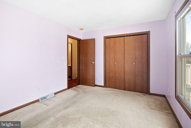 unfurnished bedroom featuring light colored carpet and a closet