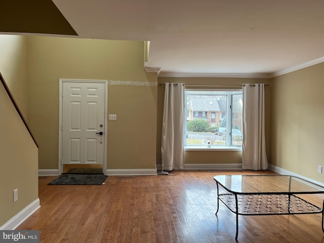 foyer entrance with crown molding and light wood-type flooring