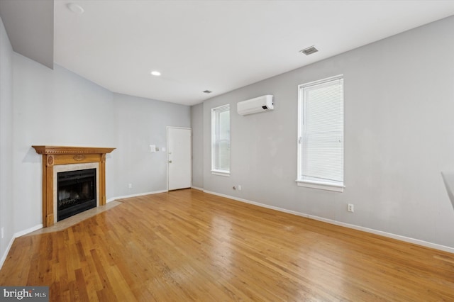 unfurnished living room with a wall mounted AC and light wood-type flooring