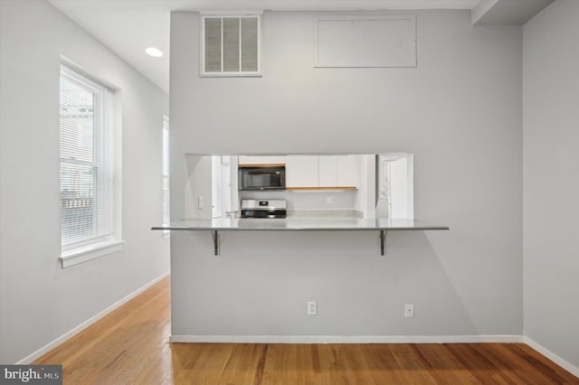 kitchen with white cabinetry, a kitchen bar, electric stove, and kitchen peninsula