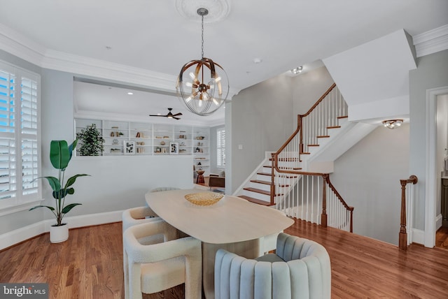 dining room with wood-type flooring, ornamental molding, and ceiling fan with notable chandelier