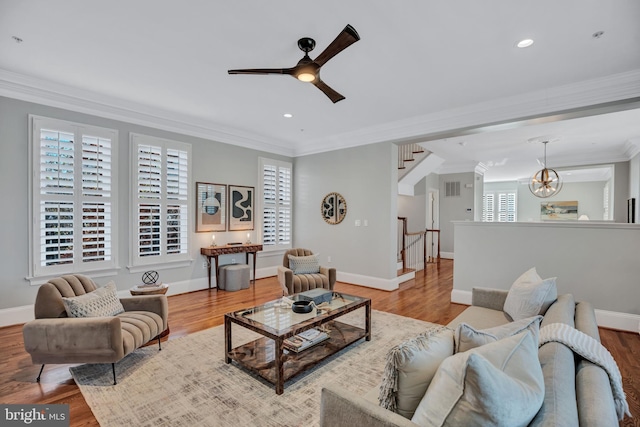 living room featuring hardwood / wood-style floors, crown molding, and ceiling fan with notable chandelier