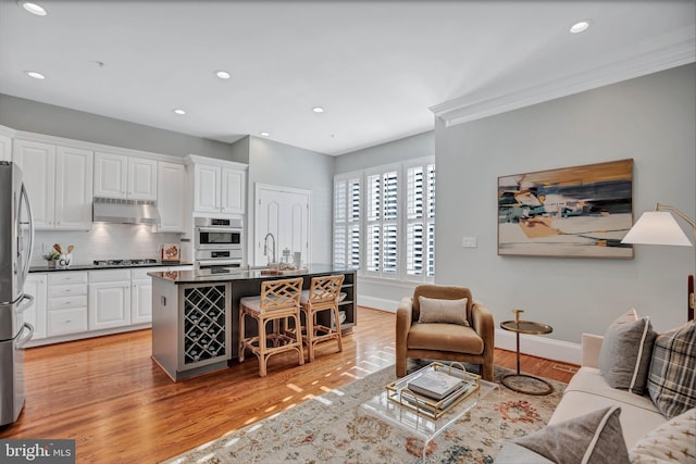 living room featuring ornamental molding, sink, and light hardwood / wood-style flooring