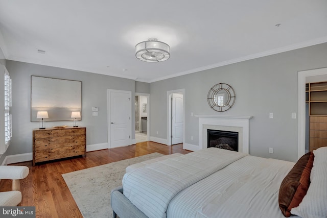 bedroom with crown molding, wood-type flooring, a spacious closet, and a closet