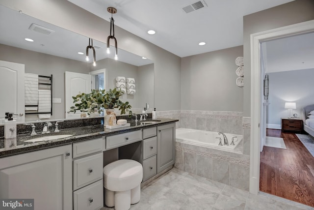 bathroom with vanity and tiled tub