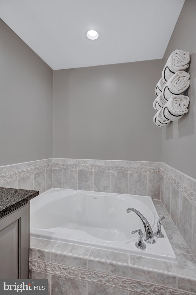 bathroom featuring vanity and tiled bath