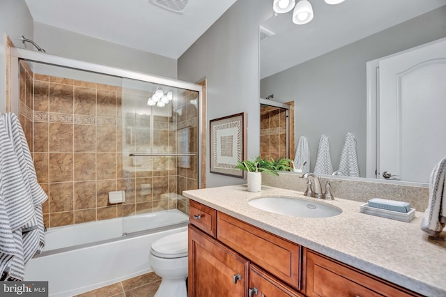 full bathroom with bath / shower combo with glass door, vanity, tile patterned floors, and toilet