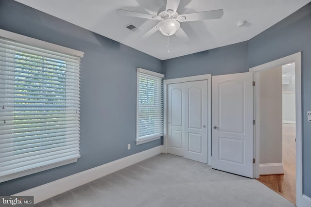 unfurnished bedroom with light colored carpet, a closet, and ceiling fan