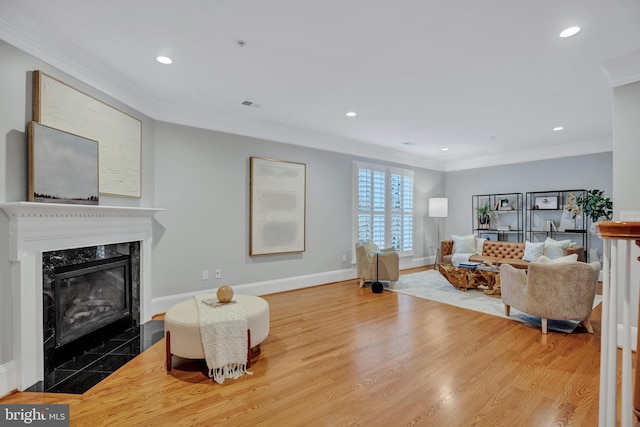 living room featuring hardwood / wood-style flooring, ornamental molding, and a fireplace