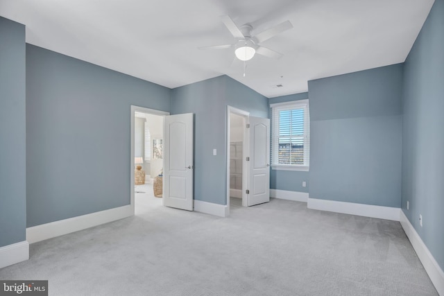 unfurnished bedroom featuring ceiling fan, a spacious closet, ensuite bath, and light carpet